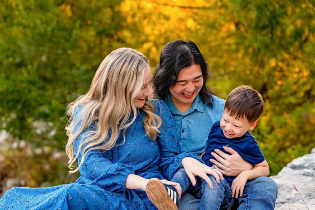 Happy family enjoying autumn outdoors with colorful trees in background.
