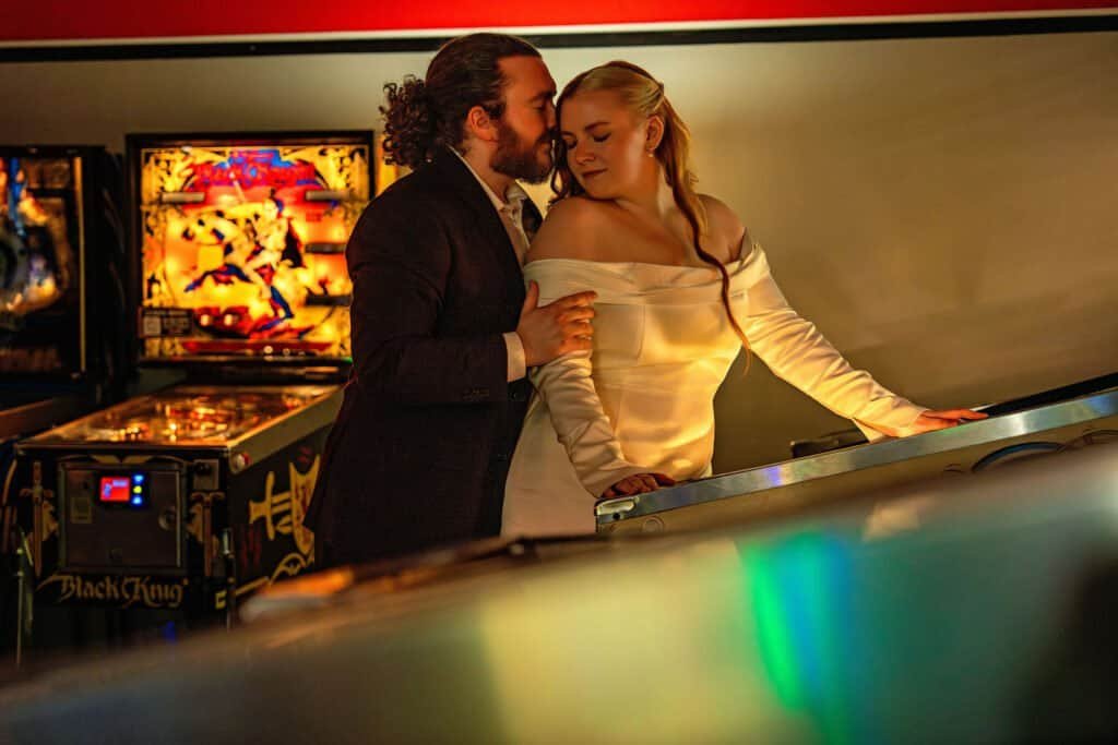 Close-up of romantic couple in vintage-style attire sharing a tender moment at arcade.